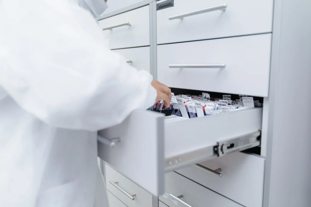 Pracownik laboratorium OIKOS wyjmujący dokumentację z szuflady archiwum